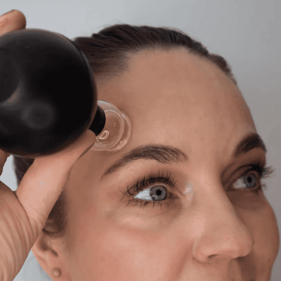 En kvinde som laver Glas Cupping med CupMe fra Organic Konjac i hendes ansigt