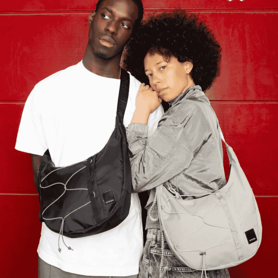 Et par der står med en HAZE Cross-Body Bag fra Kintobe i Black og Chrome Grey