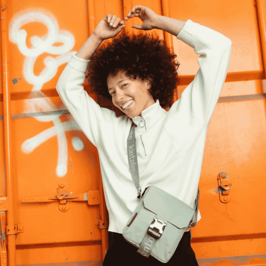 Kvinde der står med en NICO cross-body fra Kintobe i Desert Teal farven.